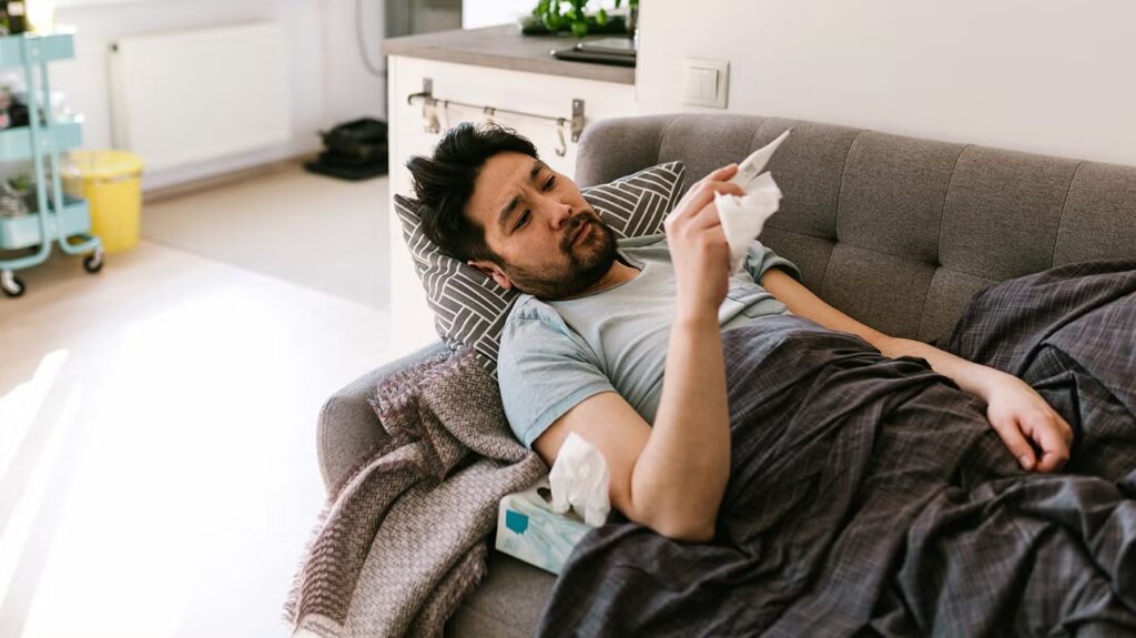 Man lying on a sofa with fever and tissue resting after contracting RSV in adults.